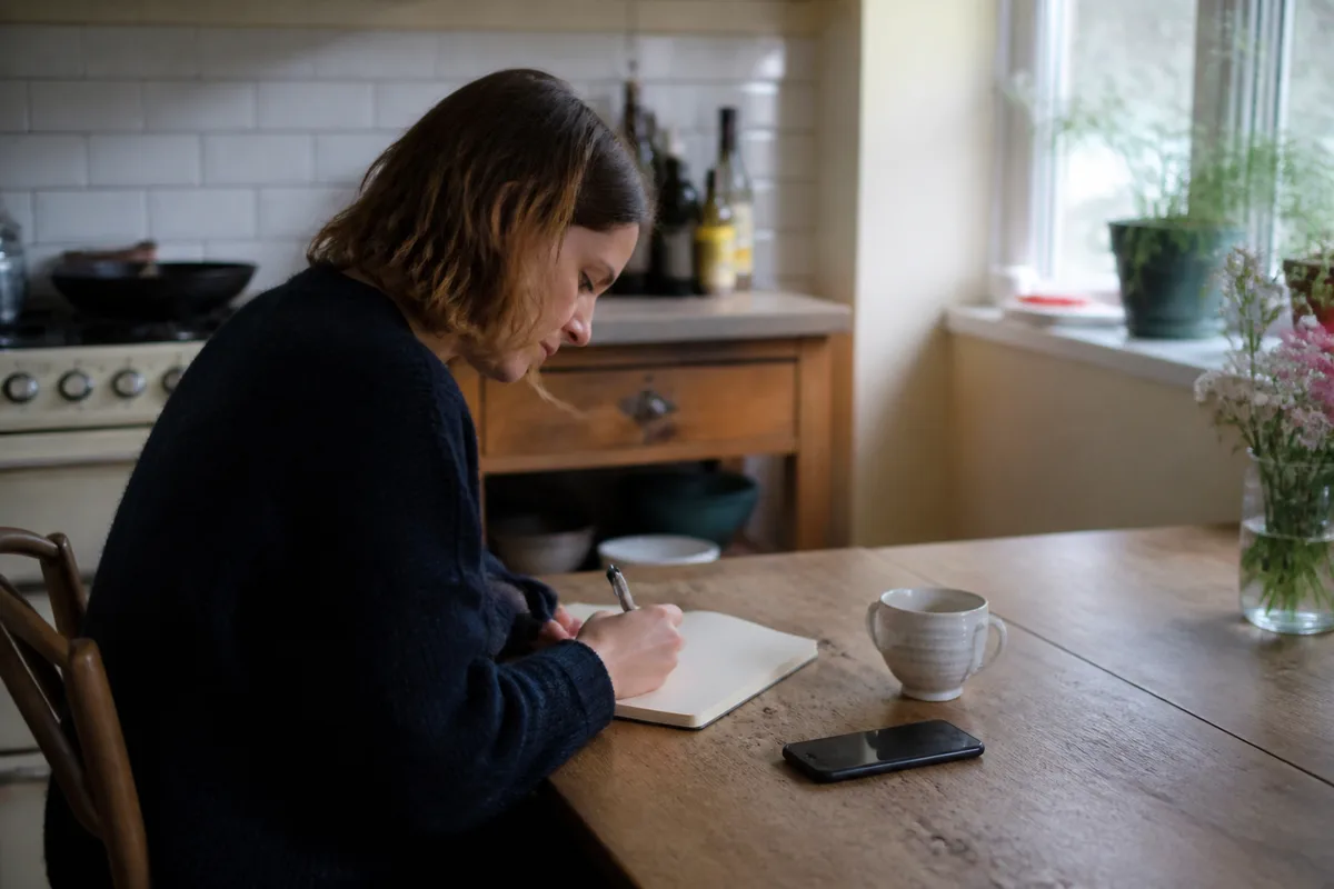 Carnet ouvert et téléphone posé sur une table après une réflexion sur la confiance dans le couple